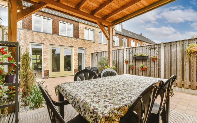 Neat paved patio with sitting area and small garden near wooden fence